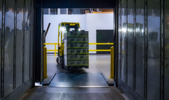 Forklift bringing a pallet into a warehouse.