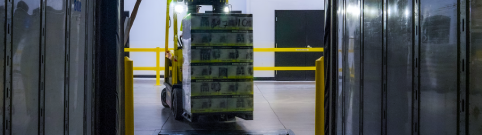 Forklift bringing a pallet into a warehouse.